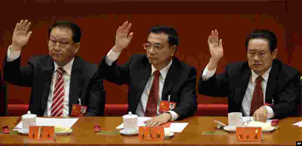 Chinese Vice Premier Li Keqiang, center, Propaganda chief Li Changchun, left, and head of Political and Legislative Affairs Committee Zhou Yongkang raise their hands during the 18th Communist Party Congress, Beijing, November 14, 2012.