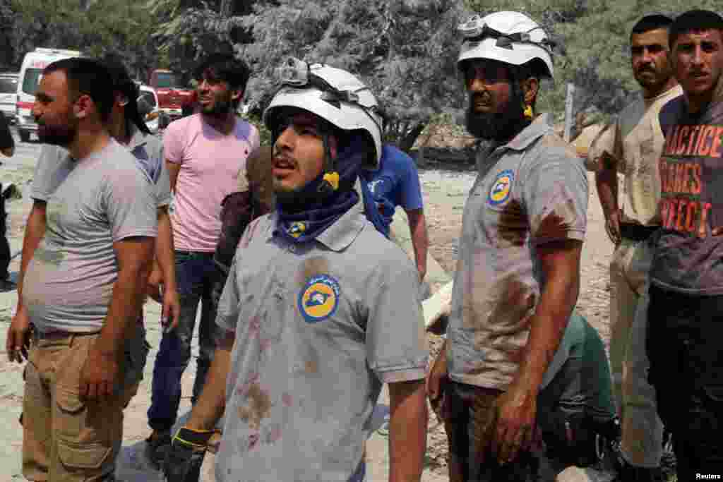 Civil Defence members with blood on their shirts stand after double airstrikes on the rebel held Bab al-Nairab neighborhood of Aleppo, Aug. 27, 2016.