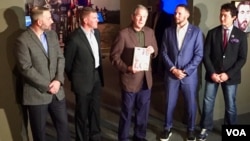 Former president George W. Bush (C) and U.S. war veterans profiled by him stand at the opening of the "Profiles of Courage" exhibit at the Bush Presidential Museum in Dallas, Texas. (K. Farabaugh/VOA)