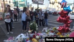Route 91 Festival goers, tourists and residents of Las Vegas placed candles, flowers, banners and photos of their loved ones at the shrine on the median just across the street from shooting site at the country music festival.