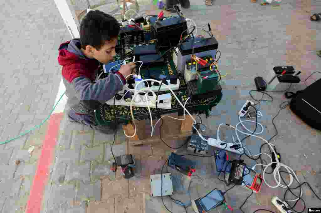 A Palestinian boy charges a mobile phone in his neighborhood which experiences power shortages, in Johr El-Deek in Gaza.