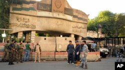 In this photo released by the Syrian official news agency SANA, Syrian soldiers and security officials gather at the scene of suicide bombings, outside police headquarters in central Damascus, Syria, Oct. 11, 2017.