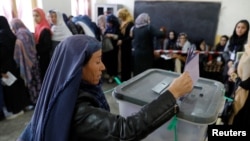 Seorang perempuan Afghan memasukkan surat suara dalam pemilihan parlemen di sebuah tempat pemungutan suara, Kabul, Afghanistan, 20 Oktober 2018. 