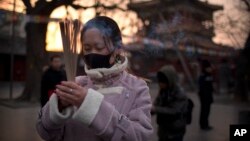 A woman holds sticks of incense as she prays at the Lama Temple in Beijing, Tuesday, Feb. 5, 2019. Chinese people are celebrating the first day of the Lunar New Year on Tuesday, the Year of the Pig on the Chinese zodiac.