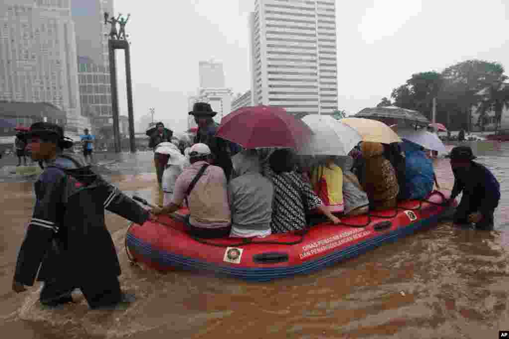Firefighters help people on a rubber boat in a flooded street, Jakarta, Indonesia, January 17, 2013.