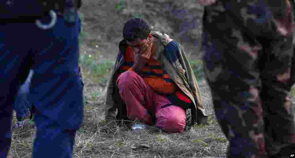 A migrant sits on the ground arrested by Hungarian police officers and soldiers after he tried to cross the border line between Serbia and Hungary in Roszke, southern Hungary. Officials announced police have detained at least 60 people under the new law, which could see illegal border crossings punished by up to three years in jail.