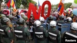 Police officers block a street as protesters march to the Cambodia National Assembly during a protest in Phnom Penh, July 13, 2015. 