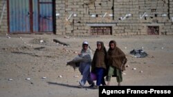 FILE - This picture taken on Nov. 9, 2021 shows children walking past an area marked as clear from mines in Nad-e-Ali village in Helmand province. 