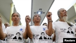 Friends and supporters wearing t-shirts with the image of lawyer Le Quoc Quan hold hands while attending a mass calling for Quan to be freed at Thai Ha church in Hanoi September 29, 2013. 