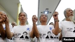 FILE - Friends and supporters wearing t-shirts with the image of lawyer Le Quoc Quan hold hands while attending a mass calling for Quan to be freed at Thai Ha church in Hanoi, Sept. 29, 2013. 