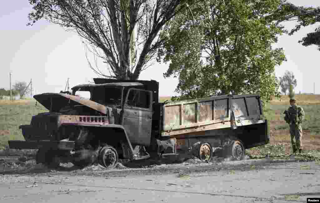 A Ukrainian soldier looks at a truck burned by recent shelling on the outskirts of the southern coastal town of Mariupol, Ukraine, Sept. 7, 2014. 