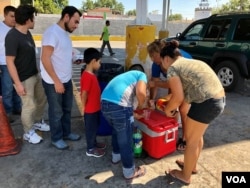 Migrantes centroamericanos hacen fila para recibir alimentos y bebidas donados por la comunidad cerca del Puente Internacional # 1 en Nuevo Laredo, México.