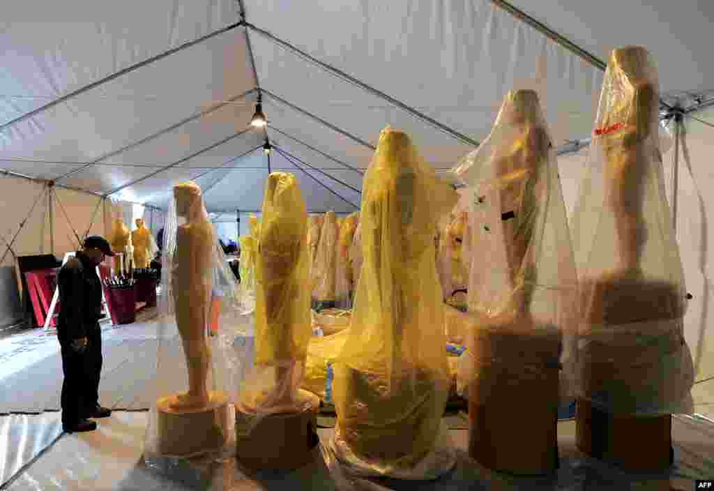 A worker stands next to the Oscar statues during a preparation work for the upcoming OSCARS, the 85th Academy Awards, at Hollywood Boulevard in Hollywood, California, on February 19, 2013. The ceremony is scheduled for February 24, 2013. 