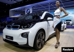 FILE - A model poses beside a BMW i3 during a media presentation during the 36th Bangkok International Motor Show in Bangkok, Thailand, March 24, 2015.