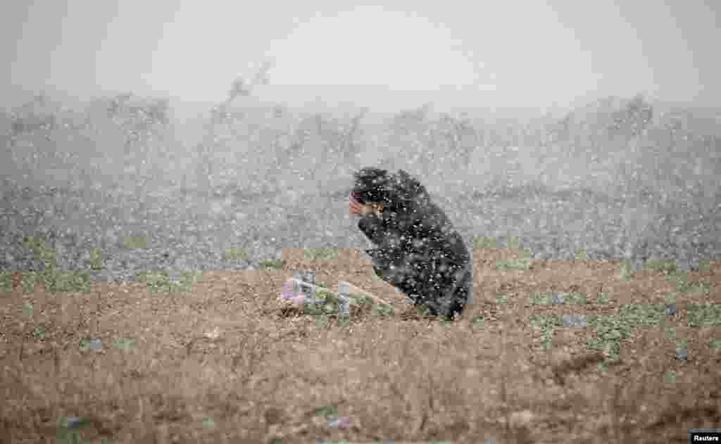 A woman prays in the snowfall for the deceased of the March 11, 2011 earthquake and tsunami in Rikuzentakata, Iwate prefecture, Japan, in this photo taken by Kyodo.