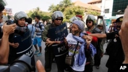 A woman from Boeung Kak Lake community is stopped by local security guards near a blocked main street near the Phnom Penh Municipality Court during villagers' gathering to call for the release of anti-governments protesters who were arrested in a police crackdown, in Phnom Penh, Cambodia, Friday, April 25, 2014. Almost two dozen Cambodian factory workers and rights activists have gone on trial in connection with labor protests earlier this year that rocked Prime Minister Hun Sen's government. (AP Photo/Heng Sinith)