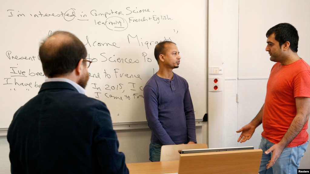 FILE - Teacher George Ferenci (L) listens to Minawar Ahmadzai (R) and Mohammed Salah Uddin Ahmed (C) during an English class for refugees at Paris' Sciences Po university in Paris, France, March 15, 2016. (REUTERS/Philip Wojazer)