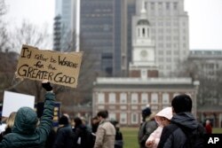 Furloughed federal worker Meghan Powell, holding sign on left, demonstrates with others against the partial government shutdown in view of Independence Hall in Philadelphia, Jan. 8, 2019.