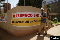 The Tunisian filmmaker Mohamed Challouf walks as he passes a banner during the Panafrican Film and Television Festival (FESPACO) in Ouagadougou, Burkina Faso, March 3, 2017.