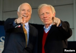 U.S. Republican presidential nominee Senator John McCain (R-AZ) (L) and U.S. Senator Joe Lieberman (I-CT) point to a sign in the crowd at a campaign rally in Grand Junction, Colorado November 4, 2008, the day of the U.S. presidential election.