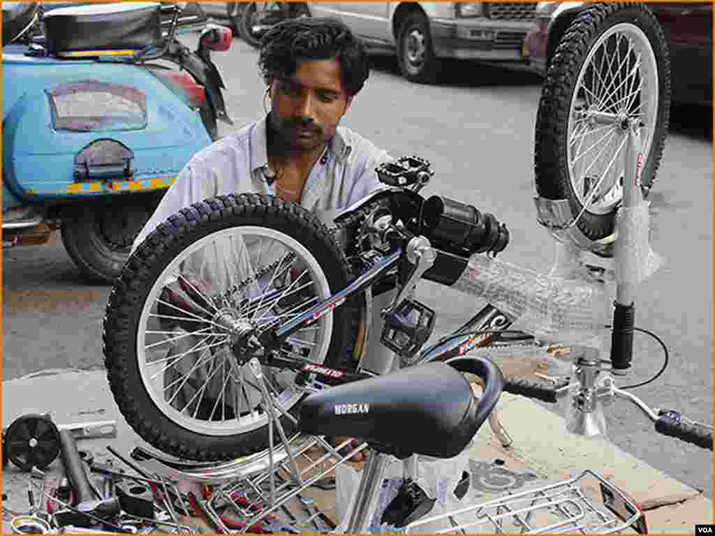 کراچی کی سائیکل مارکیٹ میں ایک شخص سائیکلوں کے پرزے جوڑتے ہوئے