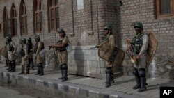 Indian paramilitary soldiers watch the funeral procession of Adil Ahmad, a civilian who was run over and killed by a security force vehicle, in Srinagar, Indian-controlled Kashmir, May 5, 2018.