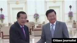 ນາຍົກລັດຖະມົນຕີກຳປູເຈຍ ທ່ານ ຮຸນ ເຊັນ, ຊ້າຍ, ນາຍົກລັດຖະມົນຕີ ລາວ ທ່ານ ທອງລຸນ ສີສຸລິດ, ຂວາ, ຈັບມືກັບໃນລະຫວ່າງການພົບປະກັນ.