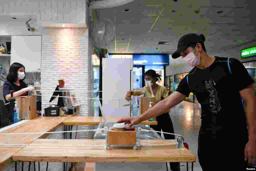 A man receives a coffee in a cart pulled by a rope as a transportation system after a cafe adopted a social distance policy for their customers amid fears of coronavirus outbreak in Bangkok, Thailand.