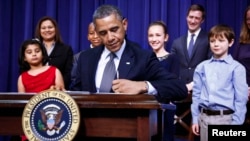 El presidente Barack Obama firma la orden ejecutiva sobre la violencia, rodeado de varios niños.