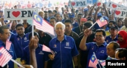 Malaysia's Prime Minister Najib Razak (C) waves a national flag as he sings patriotic songs with supporters during an election campaign rally in Rawang, outside Kuala Lumpur April 28, 2013.