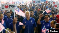 Malaysia's Prime Minister Najib Razak (C) waves a national flag as he sings patriotic songs with supporters during an election campaign rally in Rawang, outside Kuala Lumpur April 28, 2013.