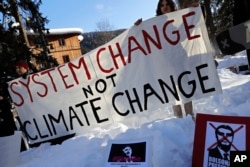 Demonstrators hold a banner during a protest outside the annual meeting of the World Economic Forum in Davos, Switzerland, Jan. 24, 2019.