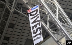 FILE - Protesters against the Dakota Access Pipeline rappel from the catwalk after placing a banner in U.S. Bank Stadium during an NFL football game between the Minnesota Vikings and Chicago Bears in Minneapolis, Jan. 1, 2017.