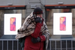 FILE - A customer waits to buy Apple's new iPhone X before its launch outside Central Universal Department Store in Moscow, Russia, Nov. 3, 2017.