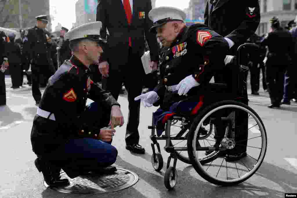 Lance Corporal James Duggan, 23, of the United States Marine Corp speaks with Sargent Michael Sulsona, 67, a United States Marine Corp Vietnam War veteran and recipient of a Purple Heart and Bronze Star, before the Veterans Day Parade in Manhattan, New York, Nov. 11, 2019.