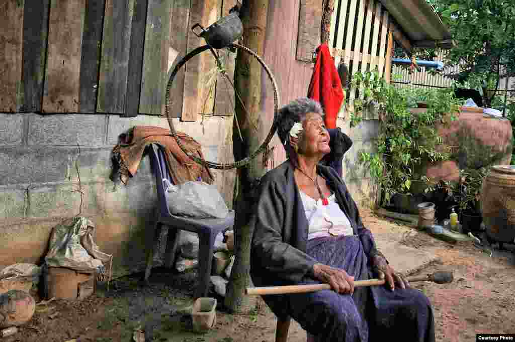 A great-grandmother, now in her nineties and having spent a lifetime rice farming, sits contentedly in her garden in northeastern Thailand without the need for internet, television or telephone, Sept. 4, 2014. (Photo taken by Matthew Richards/Thailand/VOA