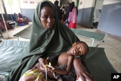 A woman holds her malnourished child on arrival at Banadir hospital in Mogadishu, Somalia, July 7, 2011