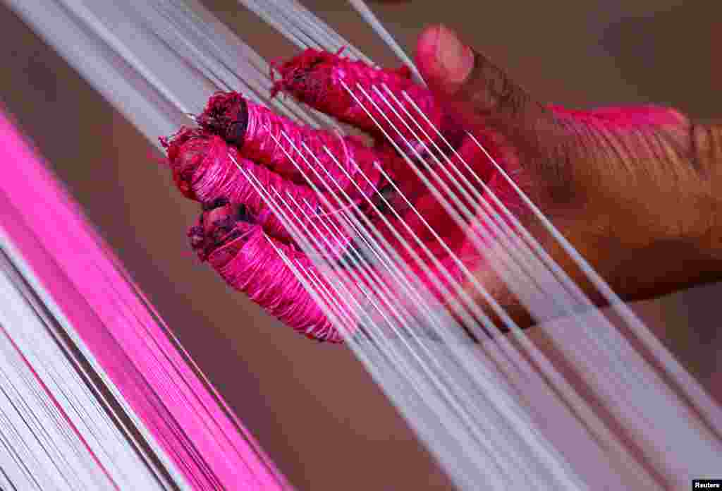 A worker applies color to strings which will be used to make kites, in Ahmedabad, India.