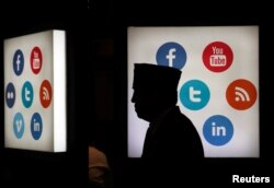 Seorang delegasi pertemuan Bank Pembangunan Islam (IDB) berjalan melintasi logo-logo platform media sosial di Jakarta Convention Center di Jakarta, 16 Mei 2016.(Foto: Reuters)