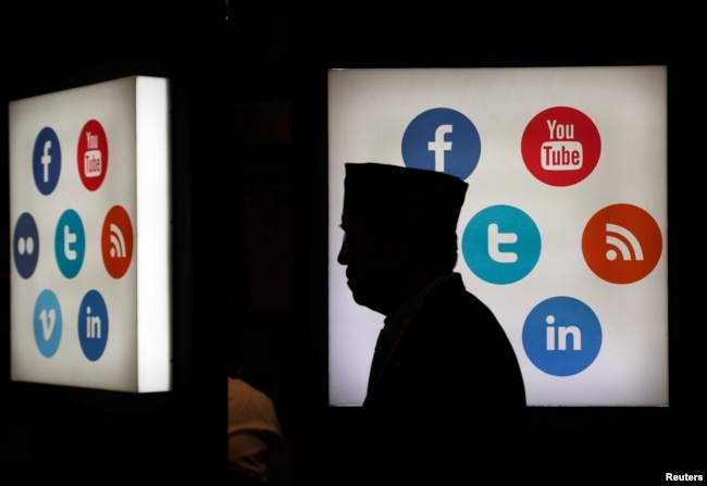 Seorang delegasi pertemuan Bank Pembangunan Islam (IDB) berjalan melintasi logo-logo platform media sosial di Jakarta Convention Center di Jakarta, 16 Mei 2016.(Foto: Reuters)