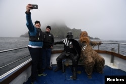 Holidaymakers take a selfie, along with Star Wars fans dressed in costume as Darth Vader and Chewbacca, on a boat trip to Skellig Island during the inaugural "May The 4th Be With You" festival in the County Kerry village of Portmagee, Ireland, May 4, 2018