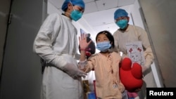 A girl, who was previously infected with the H7N9 bird flu virus, waves as she is being transferred to a public ward from the ICU at Ditan hospital in Beijing, Apr. 15, 2013.