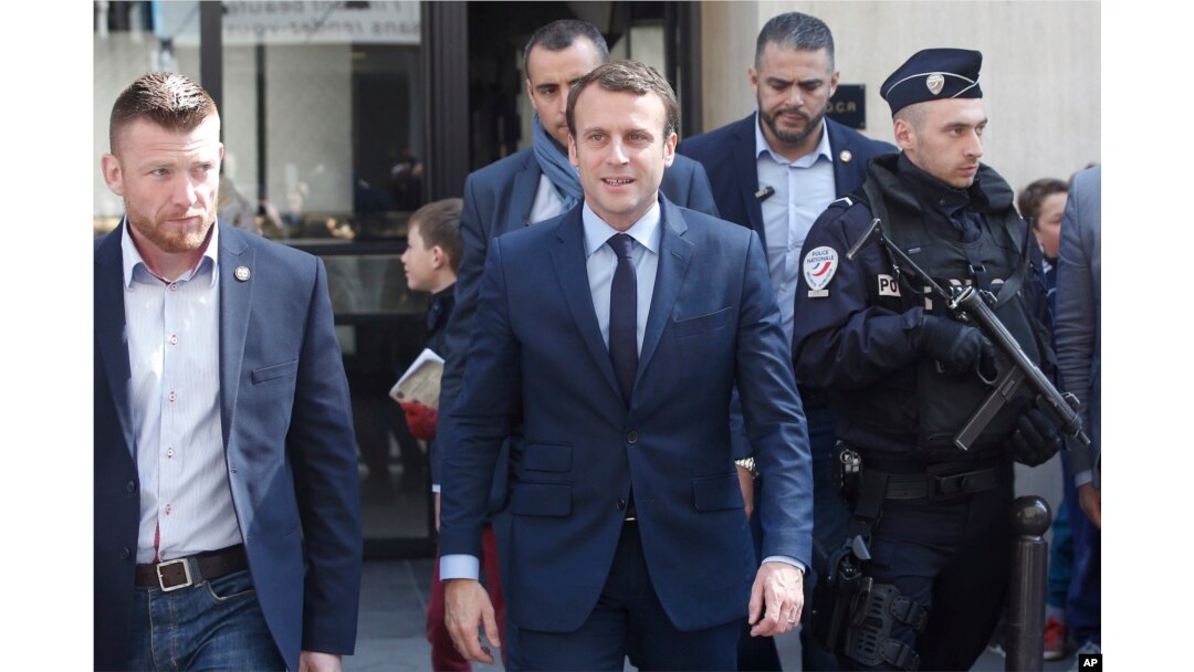 French centrist presidential candidate Emmanuel Macron, center, leaves his apartment, in Paris, April 24, 2017.