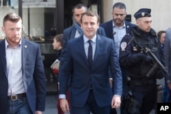French centrist presidential candidate Emmanuel Macron, center, leaves his apartment, in Paris, April 24, 2017.