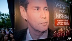 Beberapa perempuan berdiri di samping poster mendiang Jaksa Penuntut Alberto Nisman dalam peringatan satu tahun kematiannya di Buenos Aires, Argentina, 18 Januari 2016.