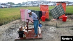 FILE - A Rohingya refugee man collects water from a tube-well near to a toilet in Cox's Bazar, Bangladesh, Nov. 15, 2017.