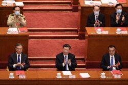 China's President Xi Jinping (C), Premier Li Keqiang (R) and Chairman of the Chinese People's Political Consultative Conference (CPPCC) Wang Yang (L) applaud after the vote on a proposal to draft a Hong Kong security law during the closing session of the