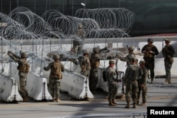 FILE - US Marines help to build a concertina wire barricade at the US-Mexico border in preparation for the arrival of a caravan of migrants at the San Ysidro border crossing in San Diego, California, Nov. 13, 2018.