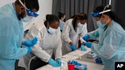 From left, health care workers Henry Paul, Ray Akindele, Wilta Brutus and Leslie Powers process COVID-19 rapid antigen tests at a testing site in Long Beach, Calif., Jan. 6, 2022.