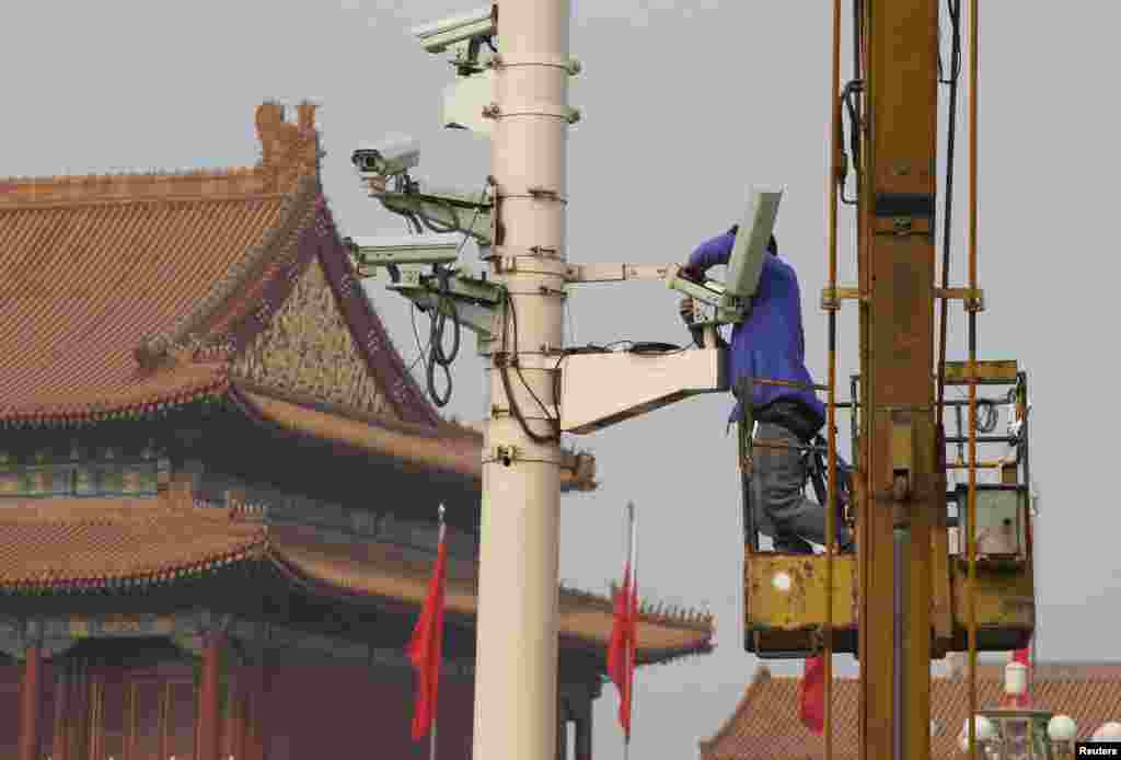 A man installs a security camera at the Tiananmen Square in Beijing, Oct. 31, 2013. 